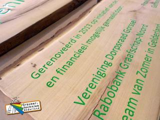 Verdiepte gravure in een houten plank, tekst in kleur